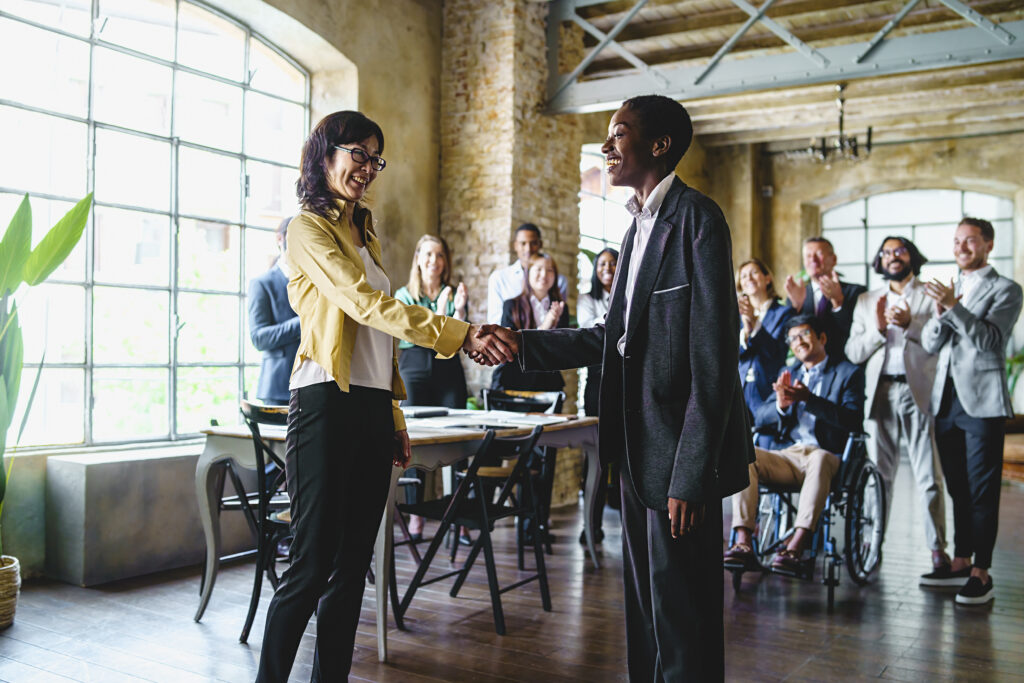 Two professionals shaking hands to celebrate a marketing job promotion.