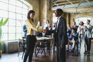Two professionals shaking hands to celebrate a marketing job promotion.